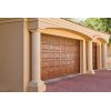 Wood colored garage door with 40 square panels and a brick driveway. Cream colored pillars on each side of the garage.