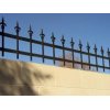 Close up of wrought iron spindle work on top of a cement wall. Pointed gate toppers.