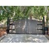 Black metal swing gate situated at the end of a concrete driveway in San Diego County, California.
