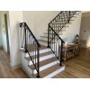 Black wrought iron stair handrail on the interior of a house. Decorative bench and doorway on each site of staircase.