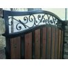 Close up of a wrought iron gate with wood panel cladding and scroll work 